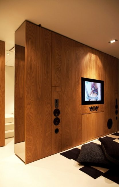 Drewniany panel TV dzieli pomieszczenie na różne strefy