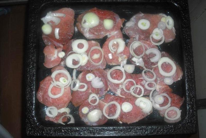 Fleisch und Zwiebeln auf ein Backblech legen