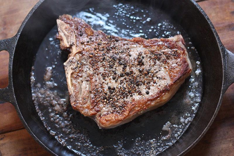 das Fleisch in einer gusseisernen Pfanne anbraten