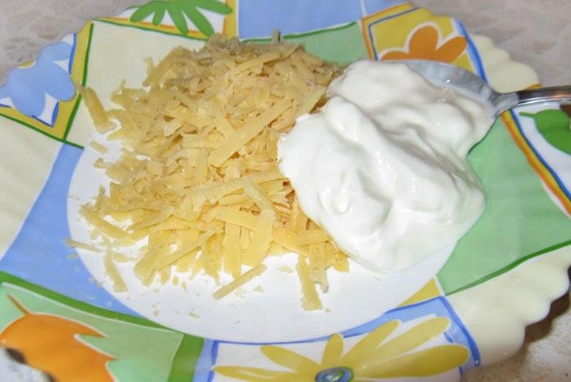 nastrouhejte sýr a promíchejte se zakysanou smetanou